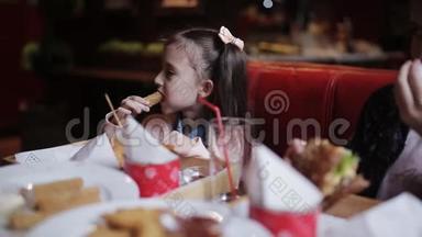 一个在快餐里吃奶酪棒的小漂亮女孩。 快餐店
